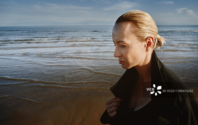 户外身穿黑外套在海边散步的美丽沉思的女人图片素材