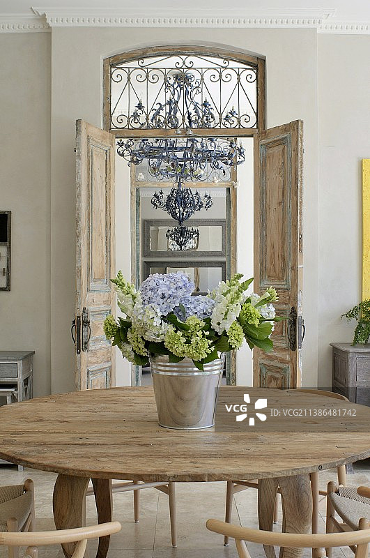 开放式室内双门前圆木桌上的花束图片素材