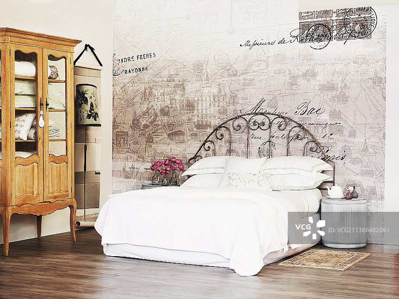 配有白色亚麻布和复古金属框架的床，靠在墙上褪色的画作和乡村巴洛克风格的展示柜旁图片素材