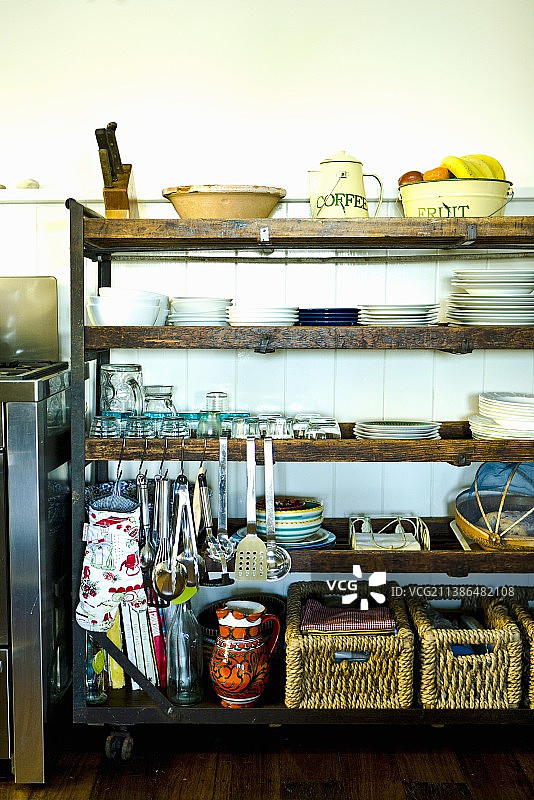 复古木架上的餐具、篮子和悬挂式厨房用具图片素材