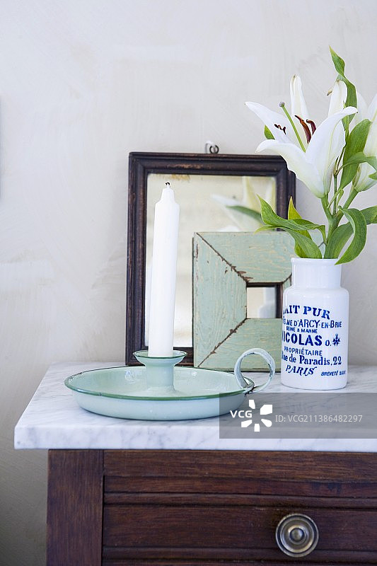 梳妆台上白色百合花瓶旁的复古烛台图片素材