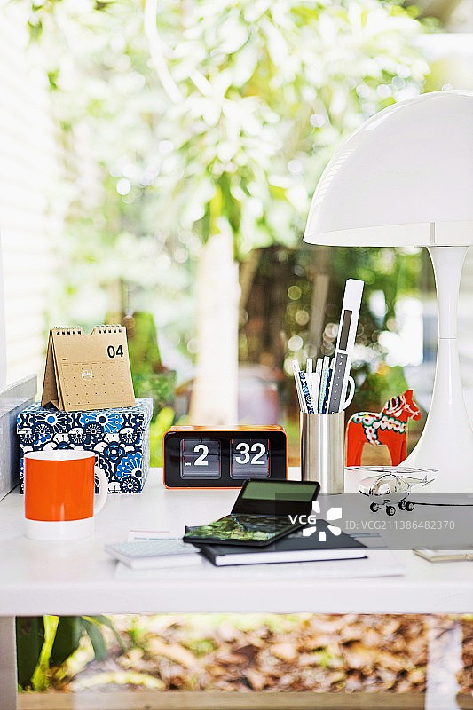 办公桌上的马克杯、闹钟和白色台灯图片素材