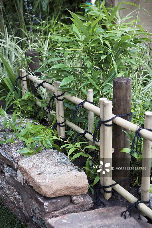 石墙和竹篱笆后的竹床图片素材