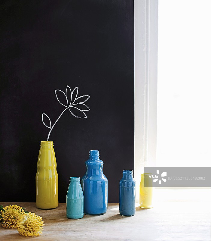 黑色墙壁上画着鲜花的黄蓝色瓶子图片素材
