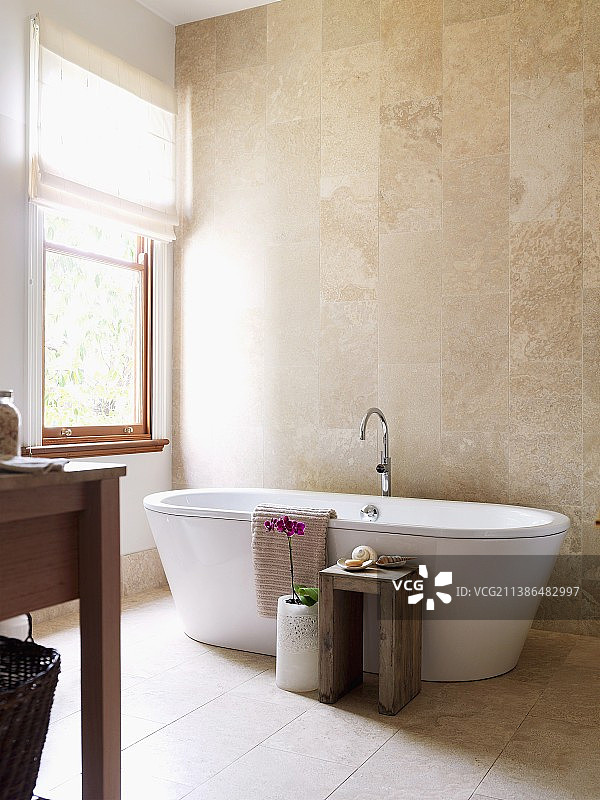 明亮浴室，独立浴缸的温暖石材色调图片素材