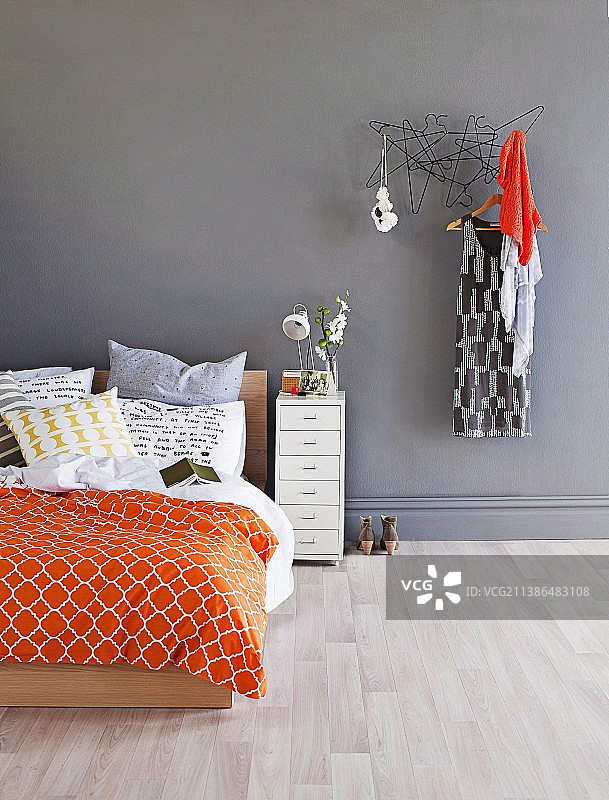 灰色墙壁旁带彩色床单的双人床和衣架图片素材