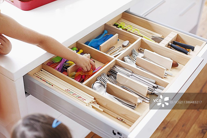 装有各种餐具的敞开式餐具抽屉，儿童的手伸向儿童餐具图片素材