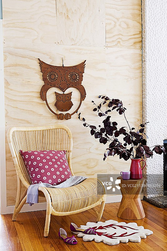猫头鹰装饰的浅色木板前的藤椅图片素材