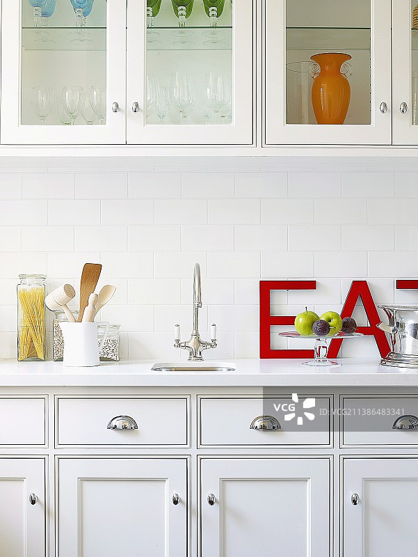 雅致的白色乡村别墅风格厨房，带壁柜；红色大字母斜靠在墙上图片素材