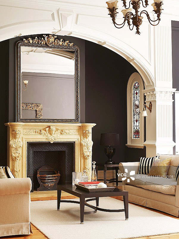 经典休息区沙发后方，雕花壁炉架上的镜子图片素材