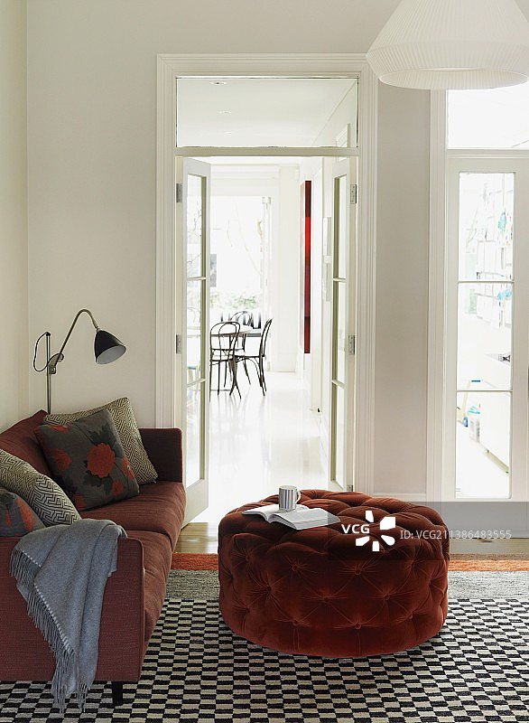 舒适阅读角的双人沙发和脚凳（背景为餐桌）图片素材