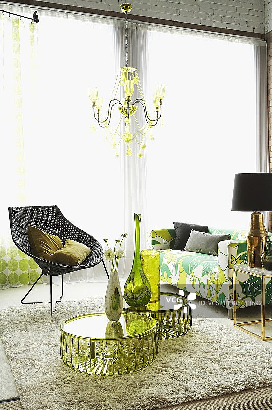 有机玻璃桌子上的花瓶和鲜花、带金属框架的柳条椅和70年代复古风格的沙发图片素材