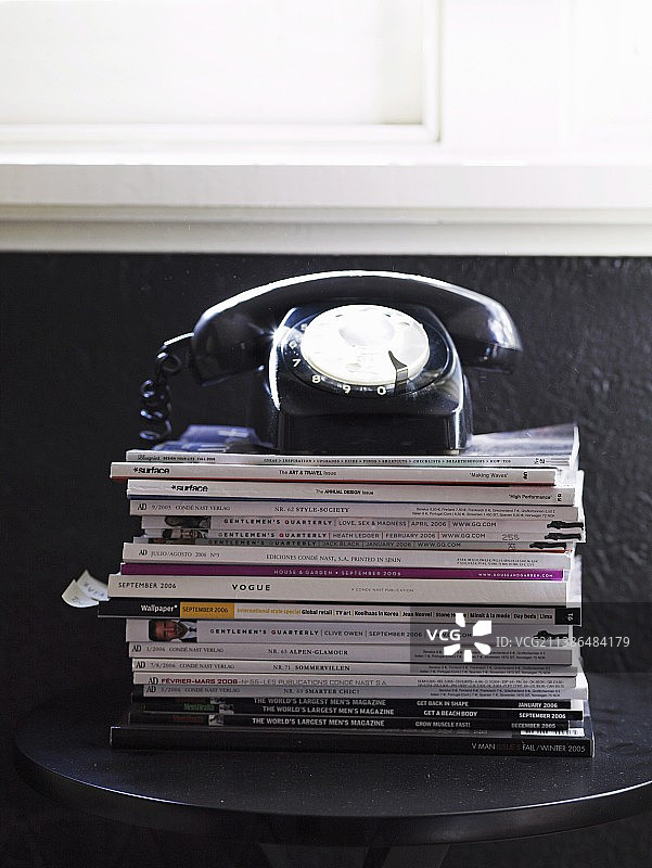 黑色墙壁和杂志堆上的复古电话图片素材