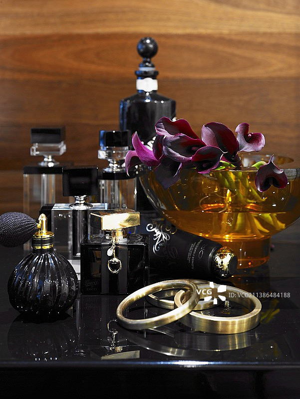 黑色梳妆台上摆放的香水瓶、兰花和手镯图片素材