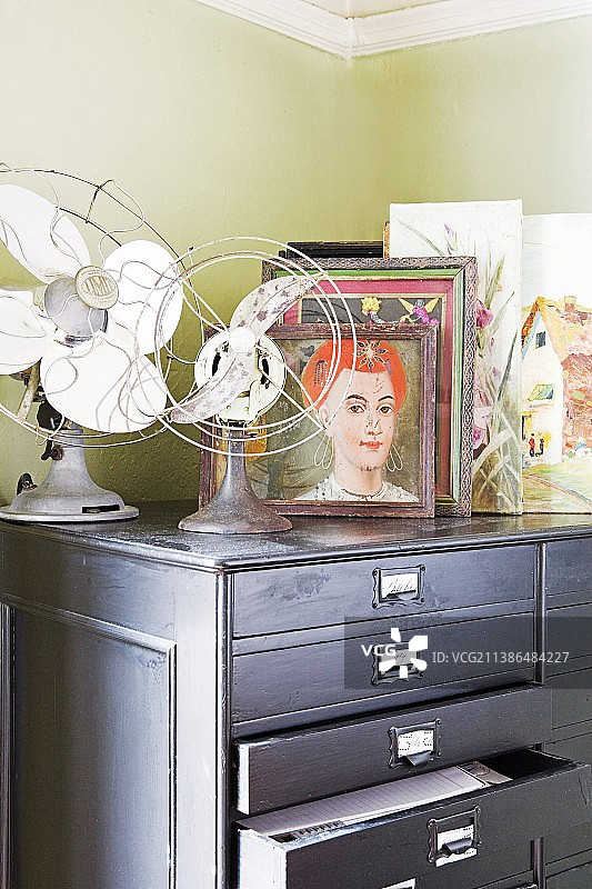 浅灰色抽屉柜上的复古风扇和照片图片素材