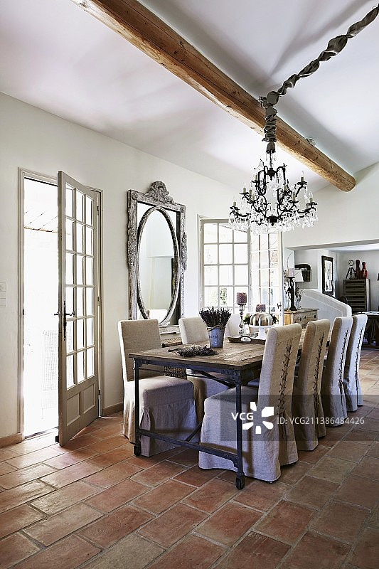 翻新后的乡村别墅：露台门边的餐桌和带松散椅套的椅子，陶土地板图片素材