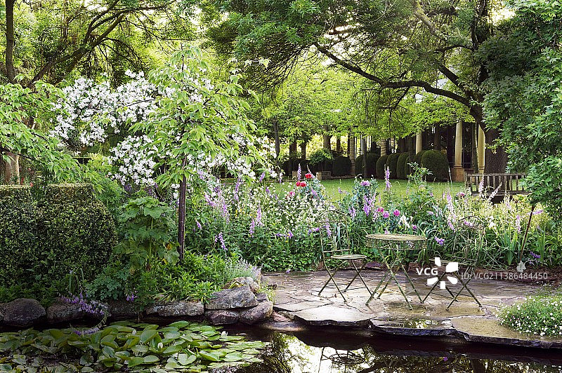石板铺成的休息区，毗邻广阔花园中的荷花池图片素材