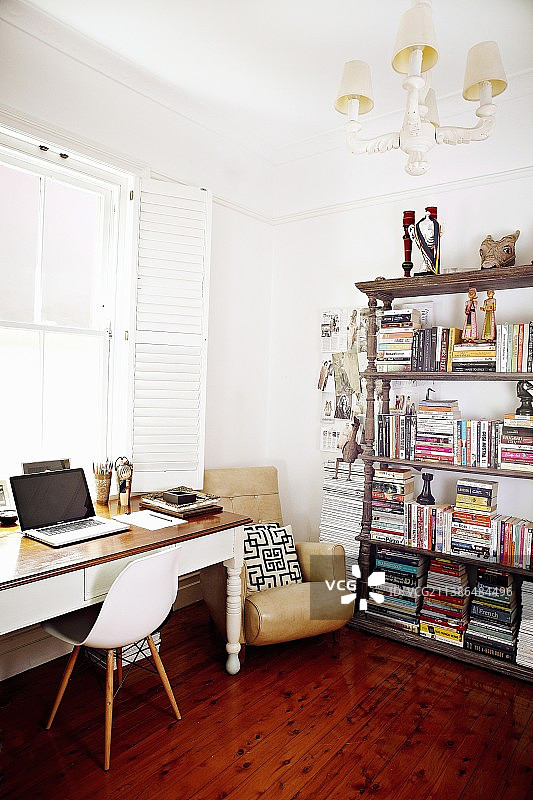 窗边包豪斯风格的椅子和桌子，旁边是扶手椅和古董书柜图片素材