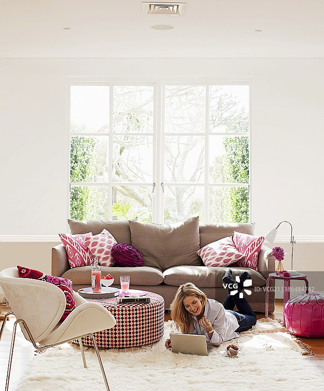 客厅中的粉色元素：沙发靠垫、鲜花、软凳和蒲团图片素材