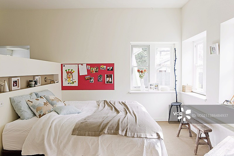 双人床的床头板作为通往更衣室的隔断：背景中有儿童在磁性钉板上的绘画和雕塑图片素材