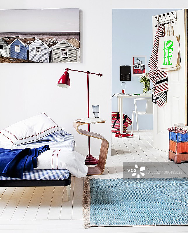 简约床铺、床头柜和红色金属复古落地灯，透过门可看到乡村风格现代书桌图片素材