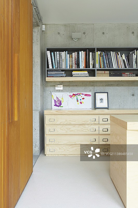现代室内，混凝土墙和木制推拉门旁的矮木抽屉柜图片素材