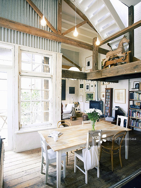 改造后的工业建筑，餐厅内设有木制画廊和白色格子窗，可欣赏到舒适的乡村别墅式起居区图片素材