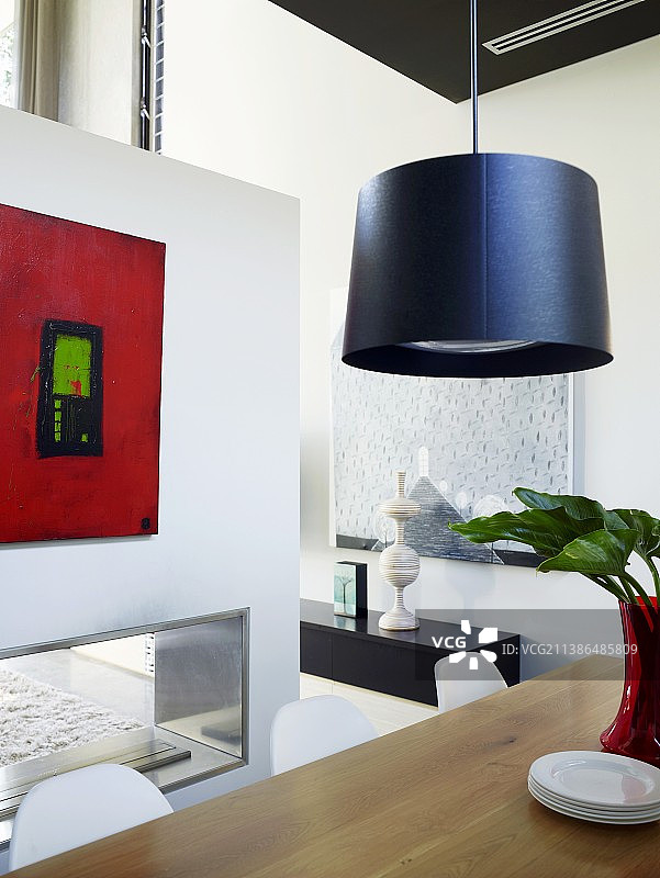 餐桌上方的吊灯和隔断墙上的现代画作图片素材