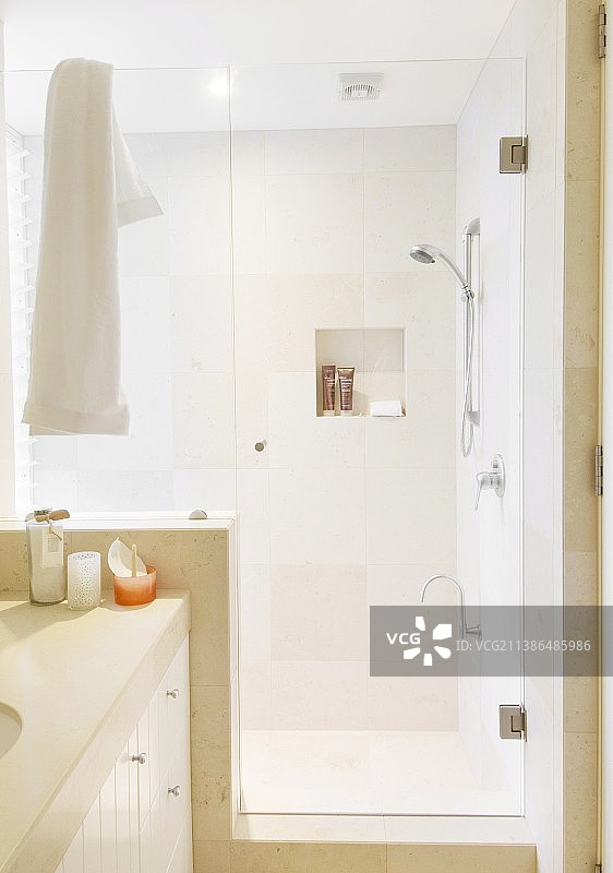 现代浴室中带玻璃门和沙色墙砖的淋浴区图片素材