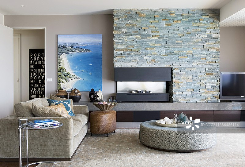 现代风格带壁炉的石墙前圆形软凳和沙发图片素材