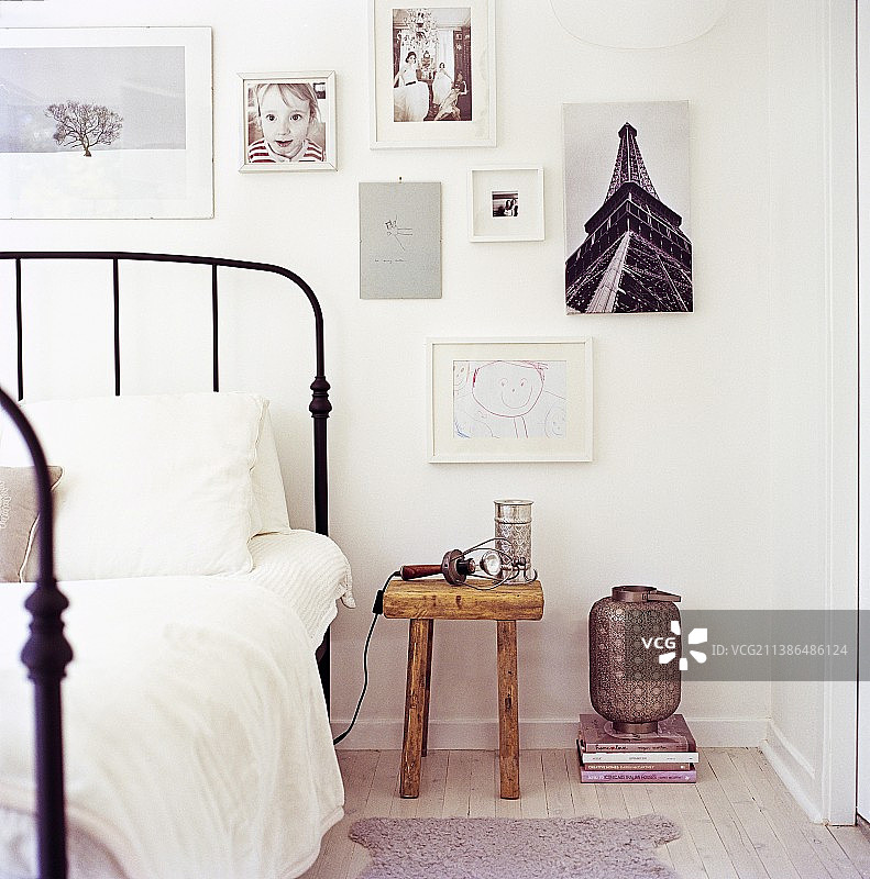 照片和图纸墙下，乡村床头柜旁的复古风格金属桌图片素材