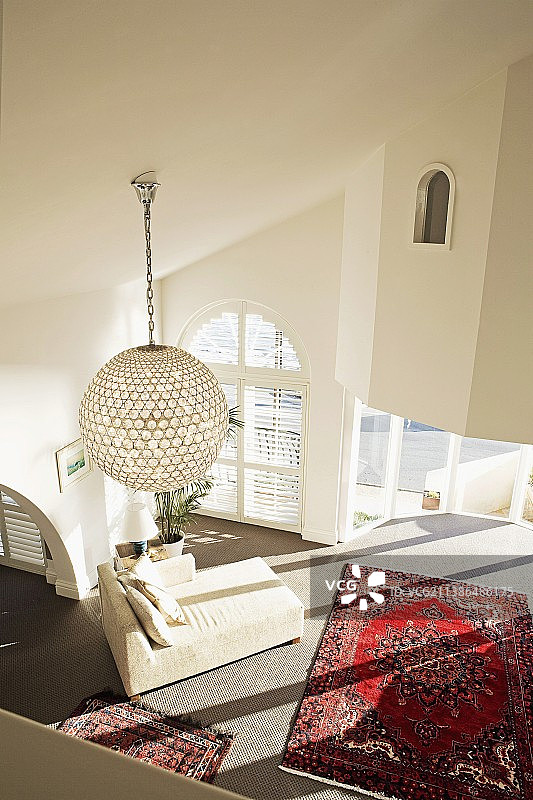 起居区域的俯视角度，配有东方地毯、现代白色躺椅和球形吊灯图片素材