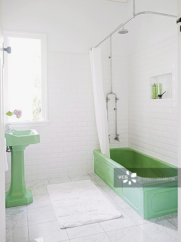 白色瓷砖浴室与大理石地板中的绿色复古立式洗脸盆和带浴帘的复古浴缸图片素材