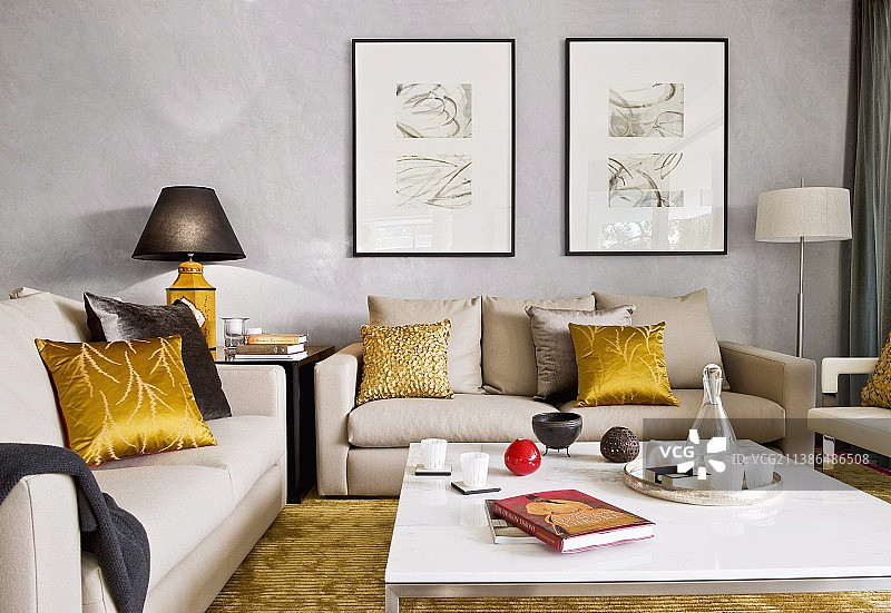 客厅里的淡色沙发组合、金色靠垫和现代咖啡桌图片素材