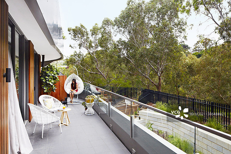 女人坐在阳台的摇椅上图片素材