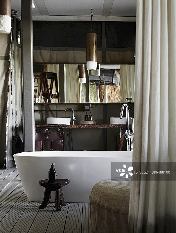 独立浴缸前的非洲木制凳子图片素材