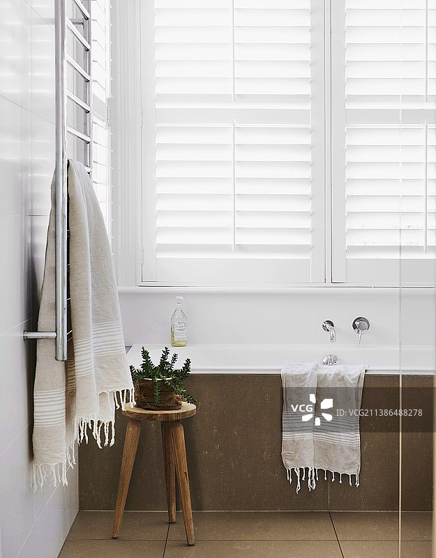 简约浴室中带有白色百叶窗和乡村木凳的石砌浴缸图片素材