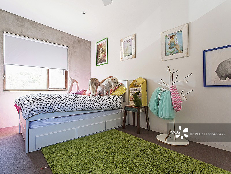 在儿童房床上与小狗玩耍的女孩图片素材