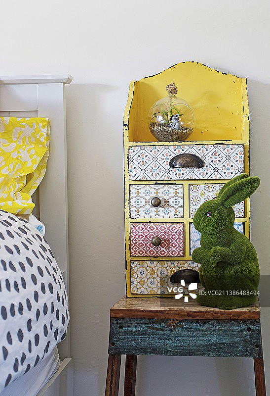 儿童房乡村床头柜上带有各种图案和绿色兔子形象的黄色复古抽屉柜图片素材