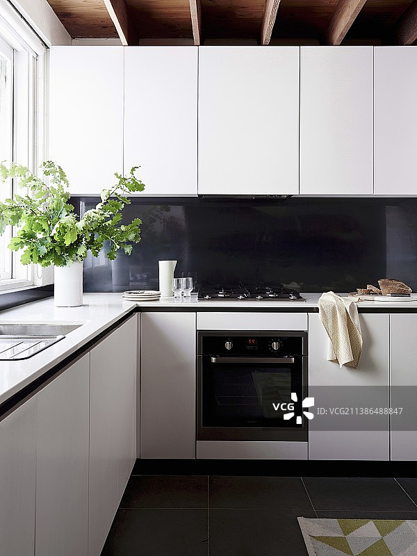 带黑色防溅板和绿橡树叶的白色转角厨房图片素材