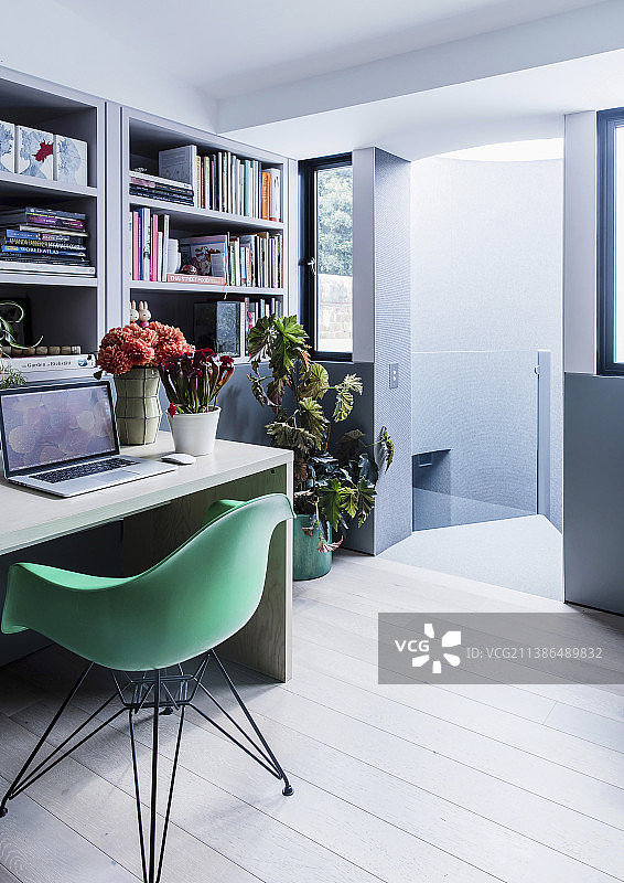 带有书柜、桌子和绿色贝壳椅的书房图片素材