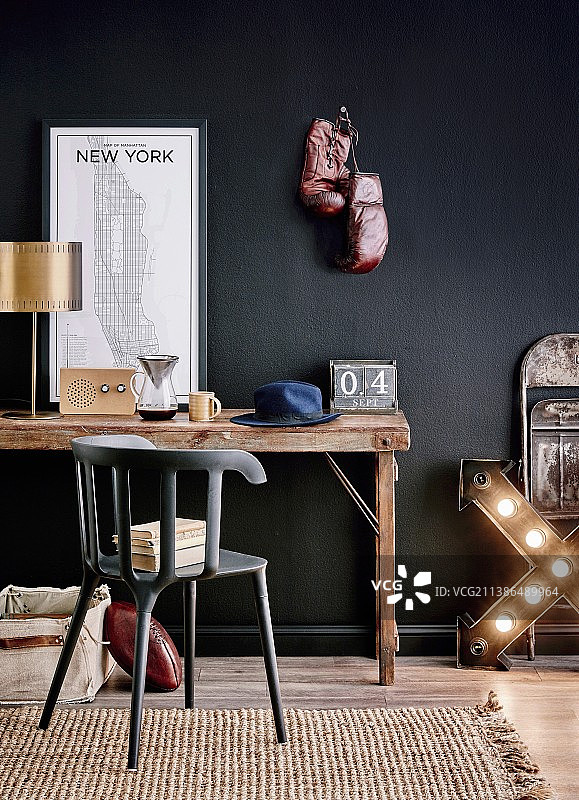 乡村风格书桌：黄铜台灯、纽约地图、收音机、咖啡壶和帽子，黑色墙壁和拳击手套图片素材