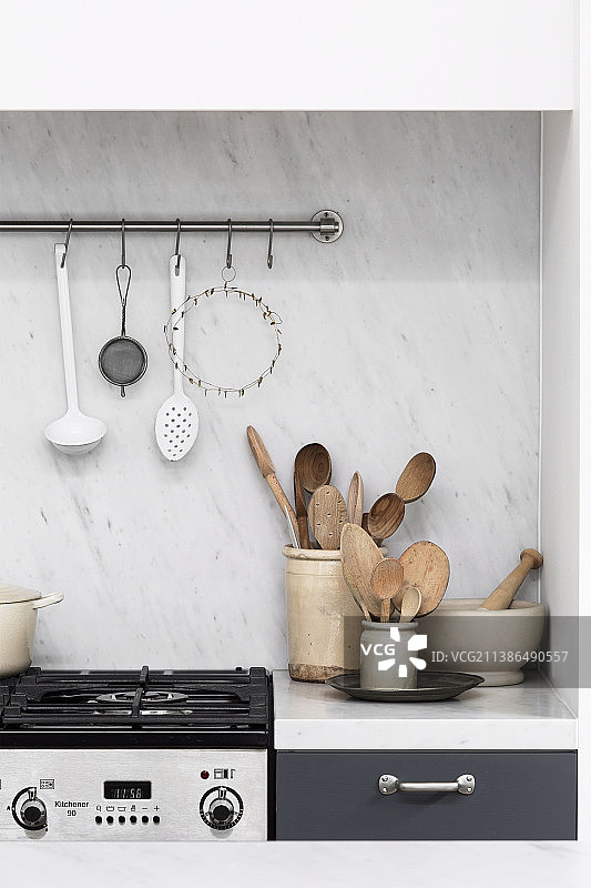 现代燃气灶旁陶罐里的木制勺子图片素材