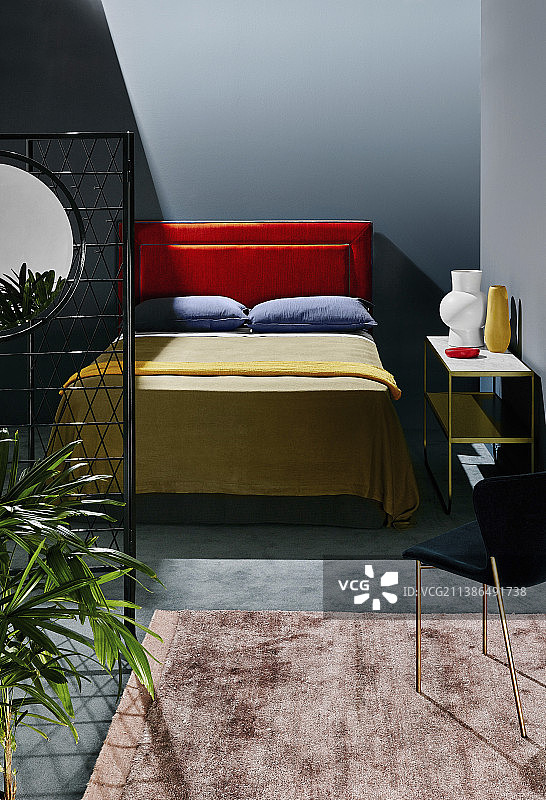 带橙色床头、橄榄绿床罩和梅子色枕头的双人床图片素材