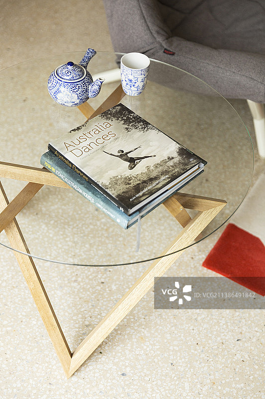 玻璃木制边桌上的书本、茶壶和杯子照片图片素材