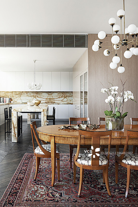 复古灯下的椭圆形餐桌椅和大理石厨房岛台图片素材