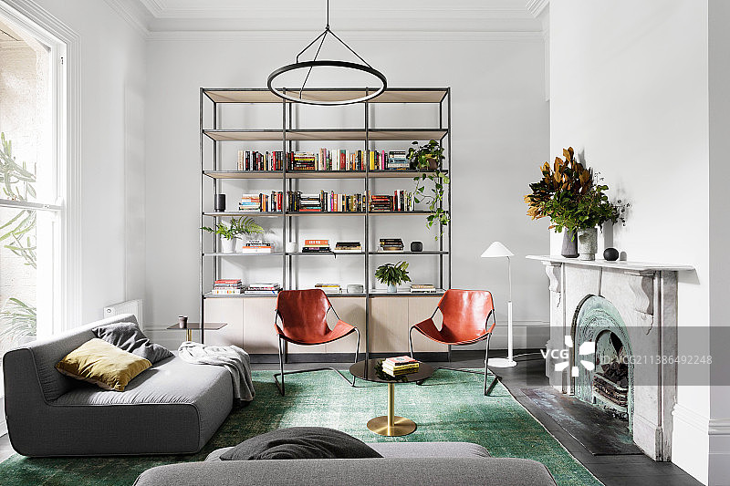 灰色软垫沙发，客厅开放式搁架和壁炉前的皮椅图片素材