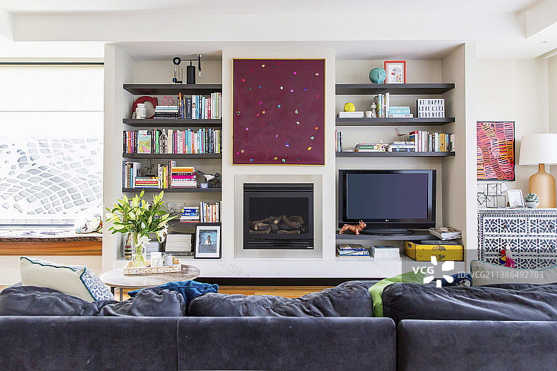 带壁炉和电视的客厅墙壁上的软垫沙发图片素材