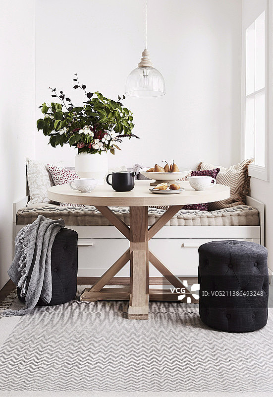 窗边壁龛长凳前的圆形木桌图片素材