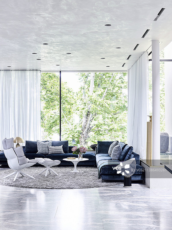 优雅的休息室，配有软垫家具和窗前的设计师扶手椅图片素材